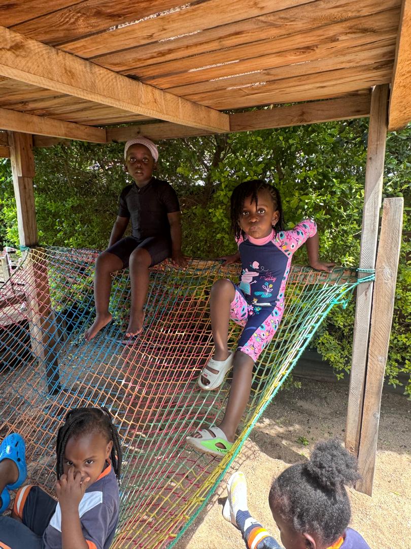 Young learners relaxing on a climbing net.